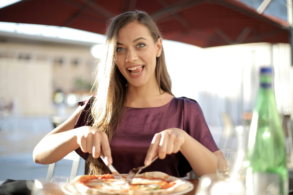 Woman slicing a pizza while smiling