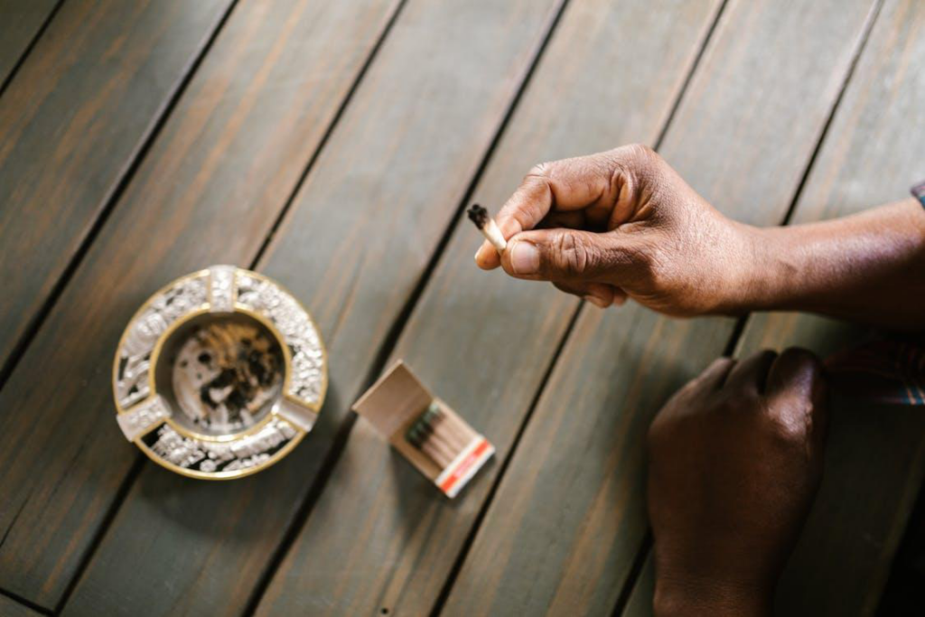 Close-up of a man holding a joint over an ash tray