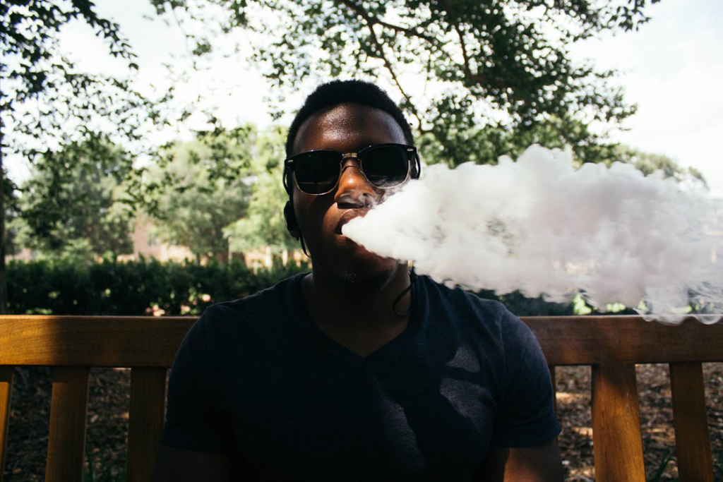 a man blowing smoke outdoors.