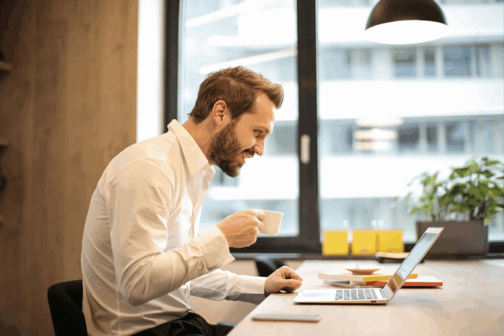 A picture of a person holding a mug while working on a laptop