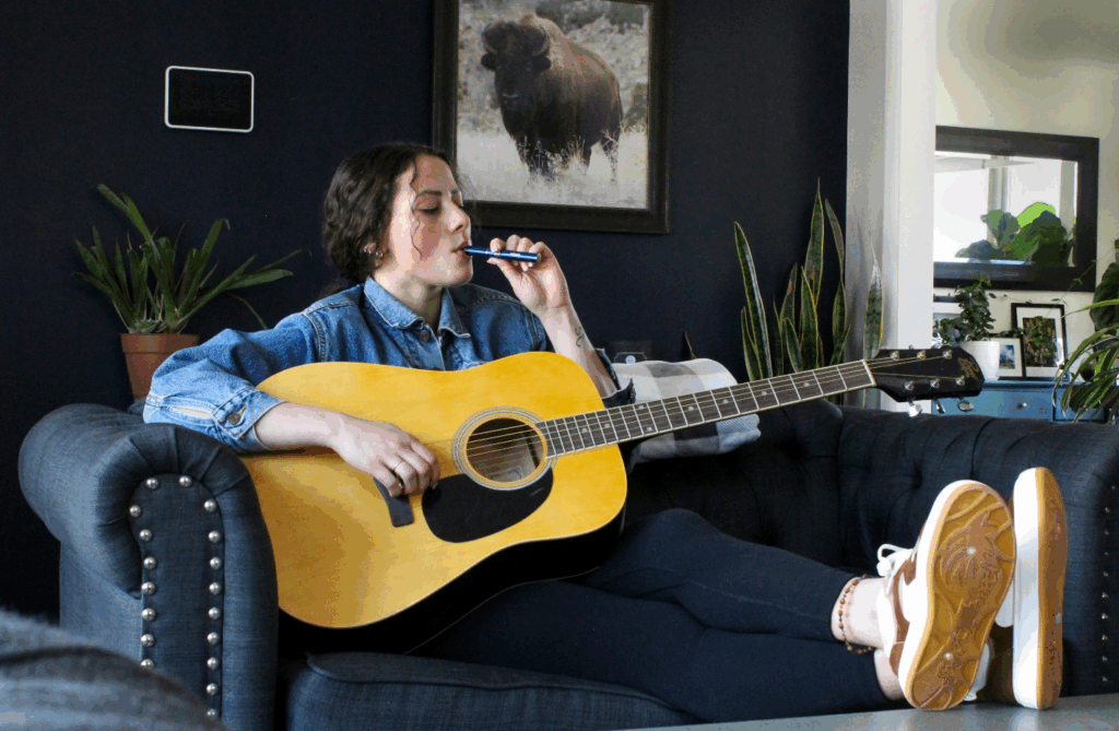 A picture of a person vaping while playing a guitar