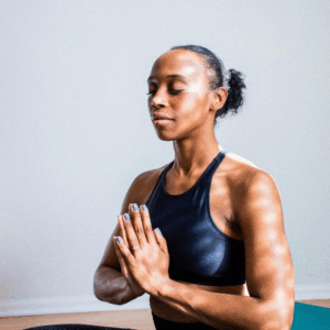 Woman meditating with eyes closed, hands together in a calm indoor setting.