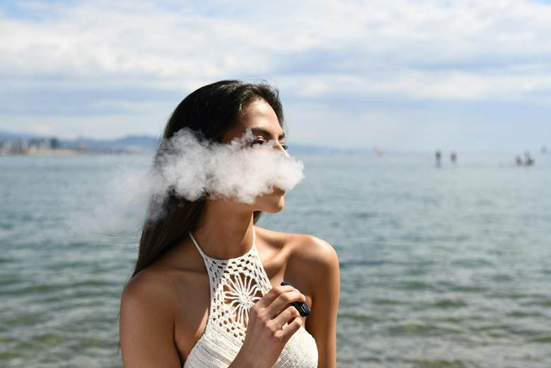 A picture of a person using a vape near the sea