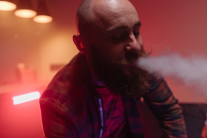 Bearded man smoking with soft diffused lighting.