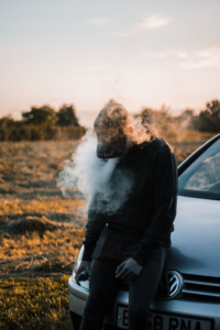Man sitting on the hood of a vehicle outdoors.