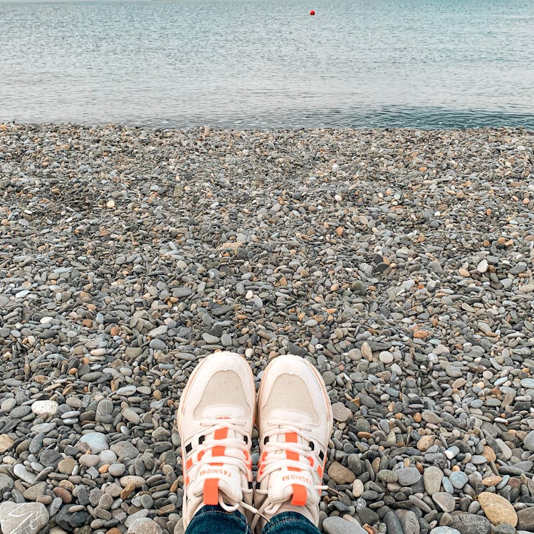 Person wearing sneakers standing on small pebbles outdoors
