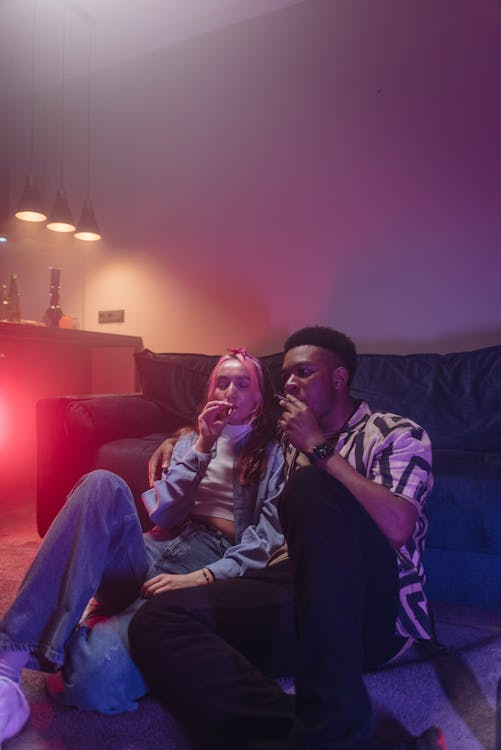 An image of a couple smoking together in a room with LED lights
