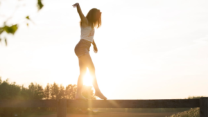 Woman walking carefully along a narrow fence outdoors