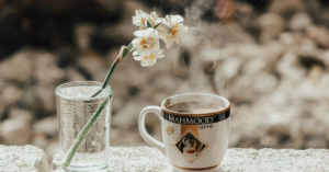 a cup of coffee and a freshly blooming flower in a glass