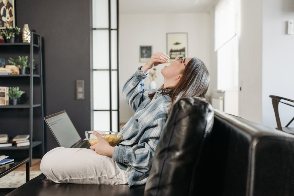 Woman with laptop having a chips bowl