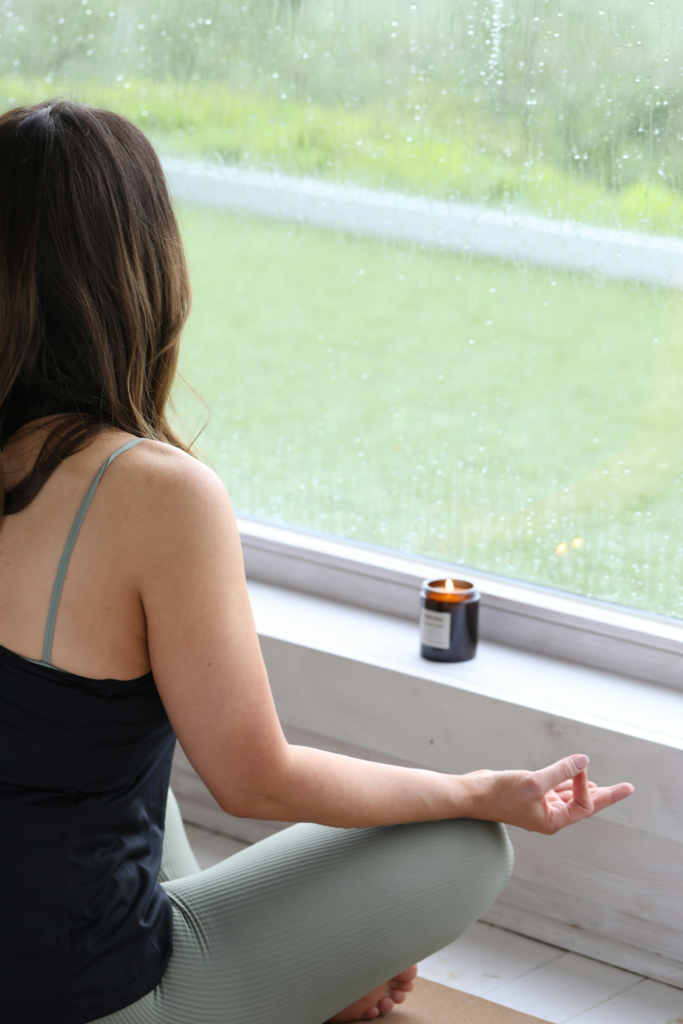 Person sitting calmly beside a rainy window during a reflective moment indoors