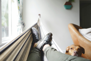 Person relaxing in a hammock near a window during a quiet moment at home