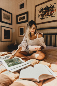 Person sitting on a bed during a quiet evening roPicture2utine with books and soft lighting