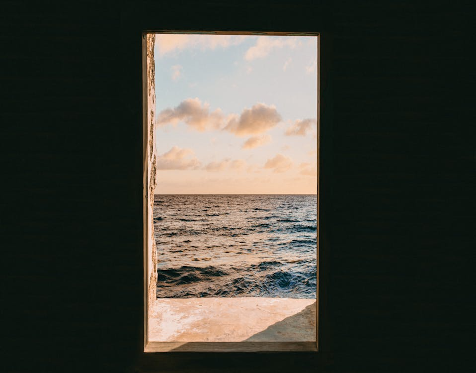An ocean view framed through an open doorway during golden hour sunset