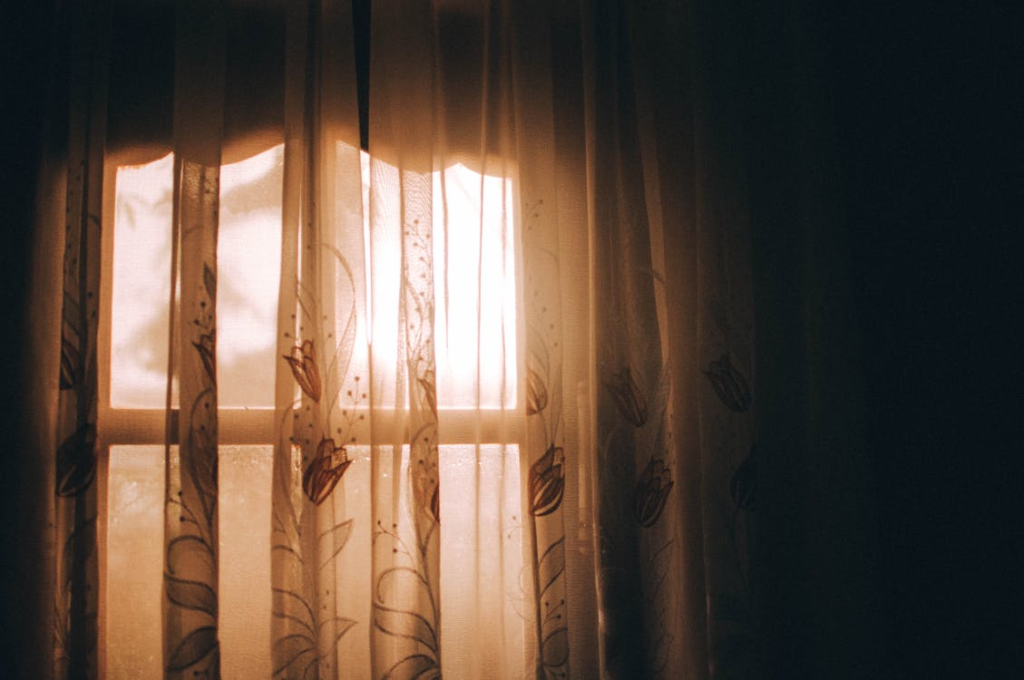 Warm morning sunlight filtering through patterned curtains creating a serene indoor scene