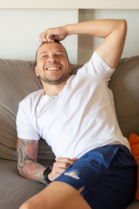 A relaxed man lounging comfortably on a sofa in casual attire on a sunny day indoors
