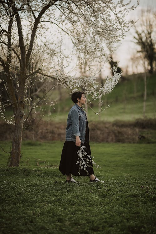  A woman walking through blooming trees in a serene spring landscape