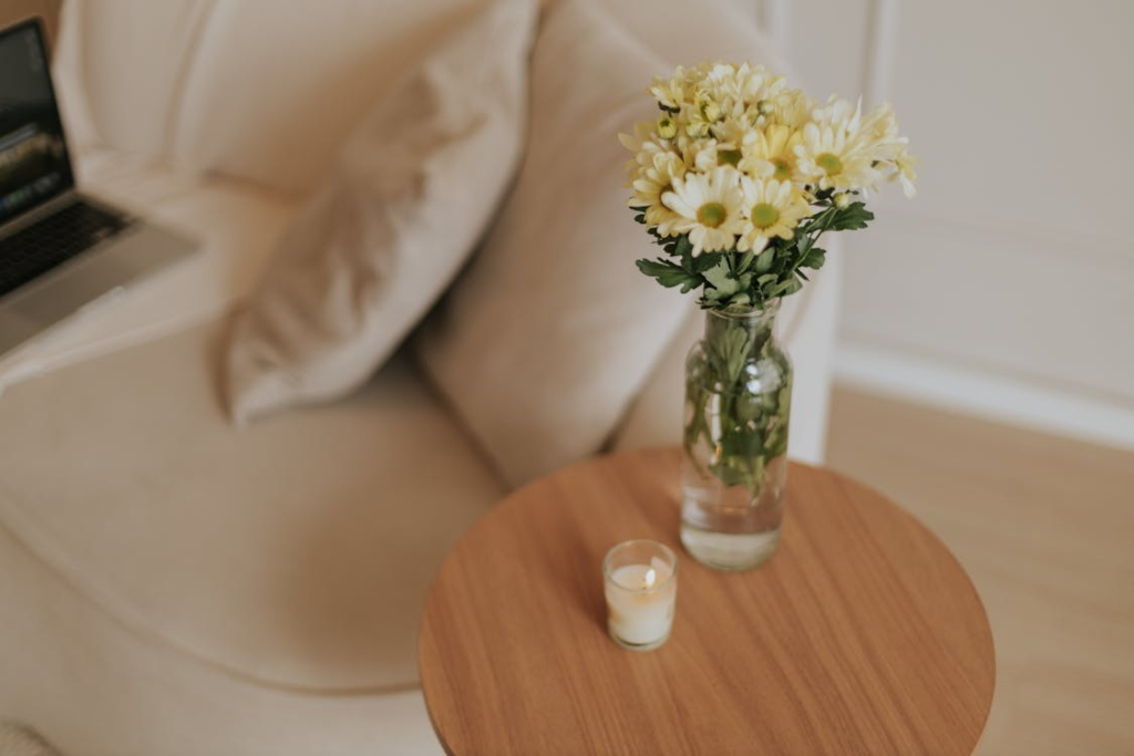 An elegant minimalist interior with daisies and a warm candle on a wooden table