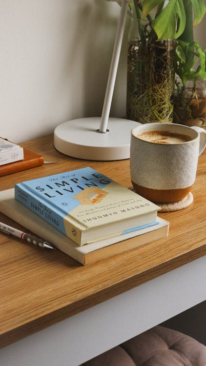 A cozy desk arrangement featuring books, a coffee cup, and small potted plants creating a personal and curated work setting.