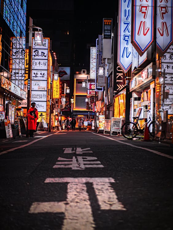 A vibrant Tokyo night street illuminated by colorful neon signs in Japanese and English text, with energetic urban atmosphere.