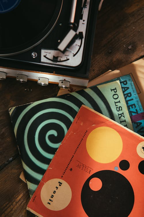 Overhead view of stacked vintage vinyl records next to a turntable on a wooden surface.