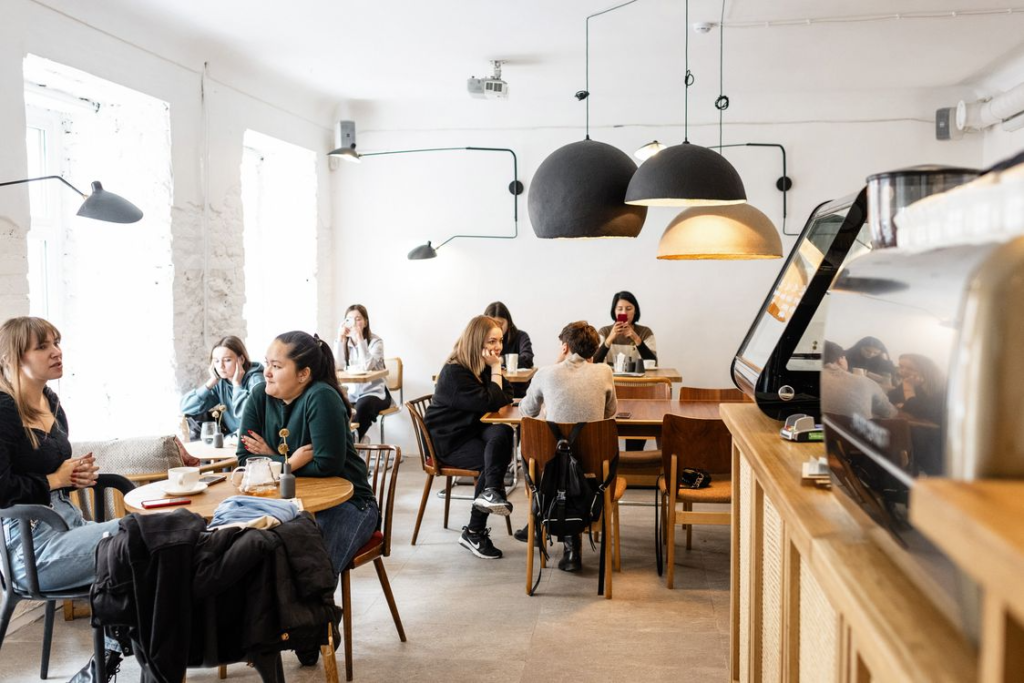 A group of diverse friends sitting and talking together in a cozy, modern cafe with warm lighting
