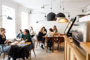 A group of diverse friends sitting and talking together in a cozy, modern cafe with warm lighting