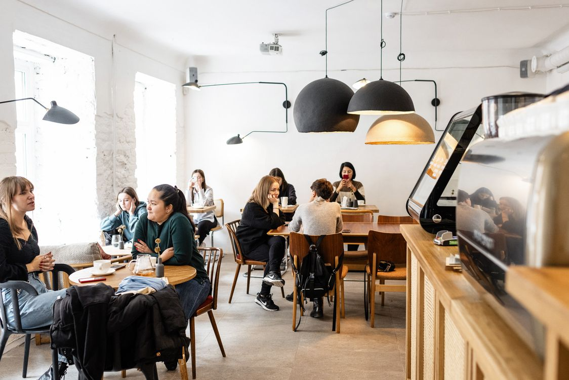 A group of diverse friends sitting and talking together in a cozy, modern cafe with warm lighting