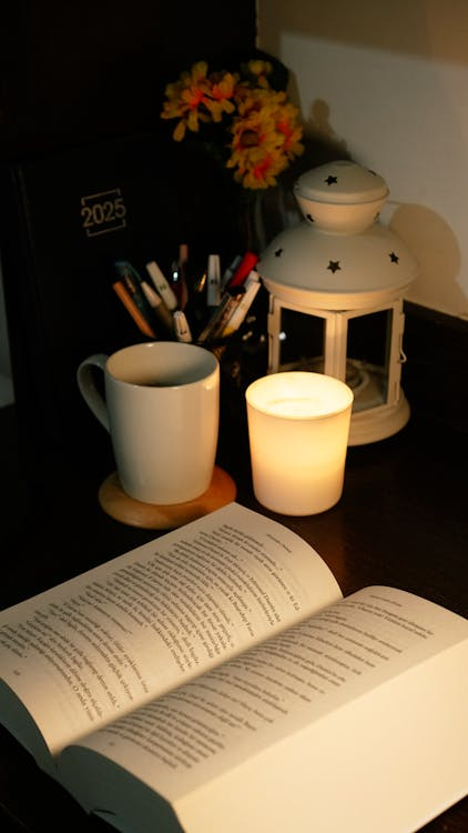 A warm and inviting reading nook lit by candlelight, featuring books, journals, and personal items for cozy evenings.