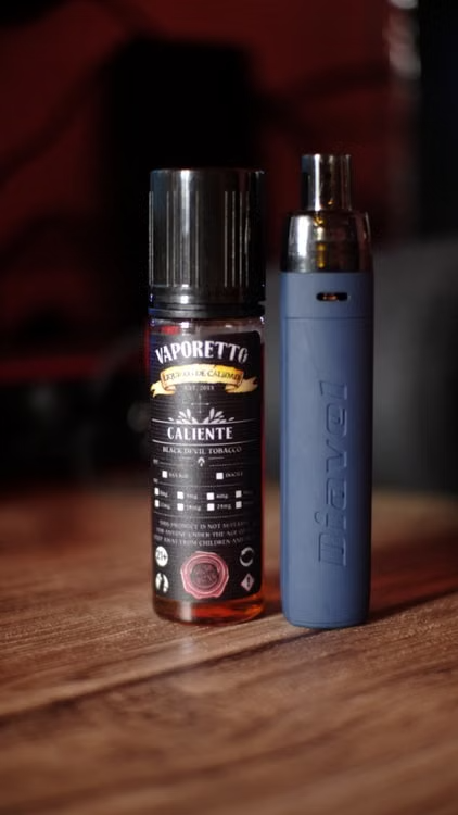 A sleek cannabis digital art disposable vape and its liquid container resting on a wooden table