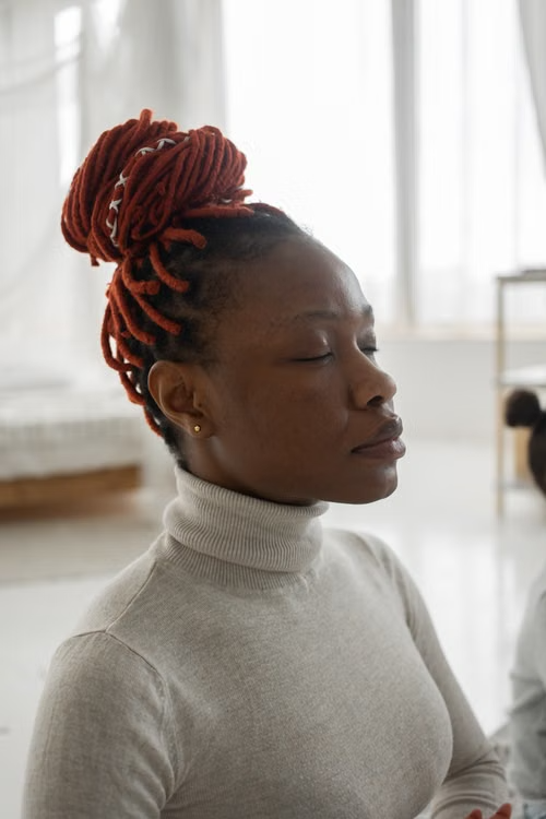 A woman meditating calmly with her eyes closed at home, settled and at ease