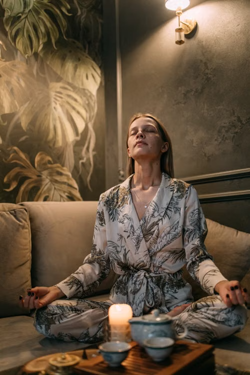 A woman sitting on her couch while meditating, taking a quiet moment to herself