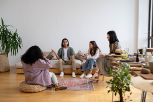 A group of people sitting and talking together in a living room, comparing notes