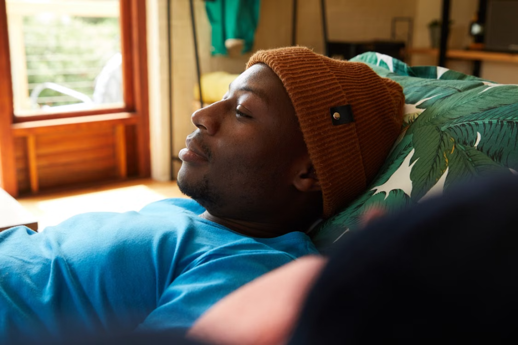 A man relaxing thoughtfully on a sofa at home, taking it easy